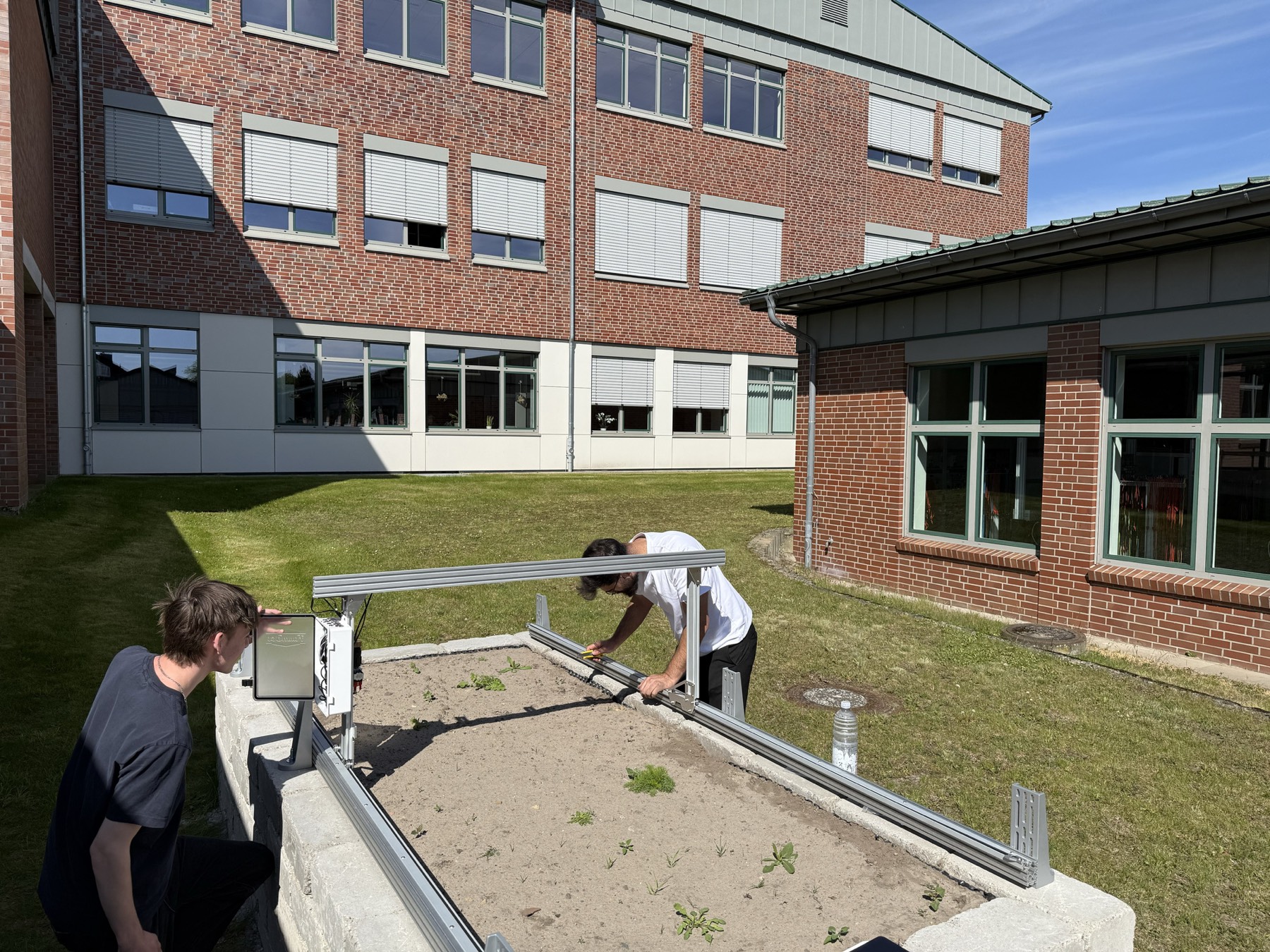 Schülerinnen und Schüler am FarmBot vor dem Schulgebäude